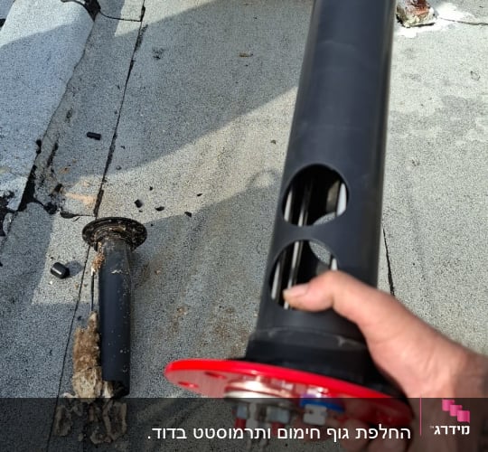 חלקי דוד שמש על גג, יד מחזיקה רכיב שחור